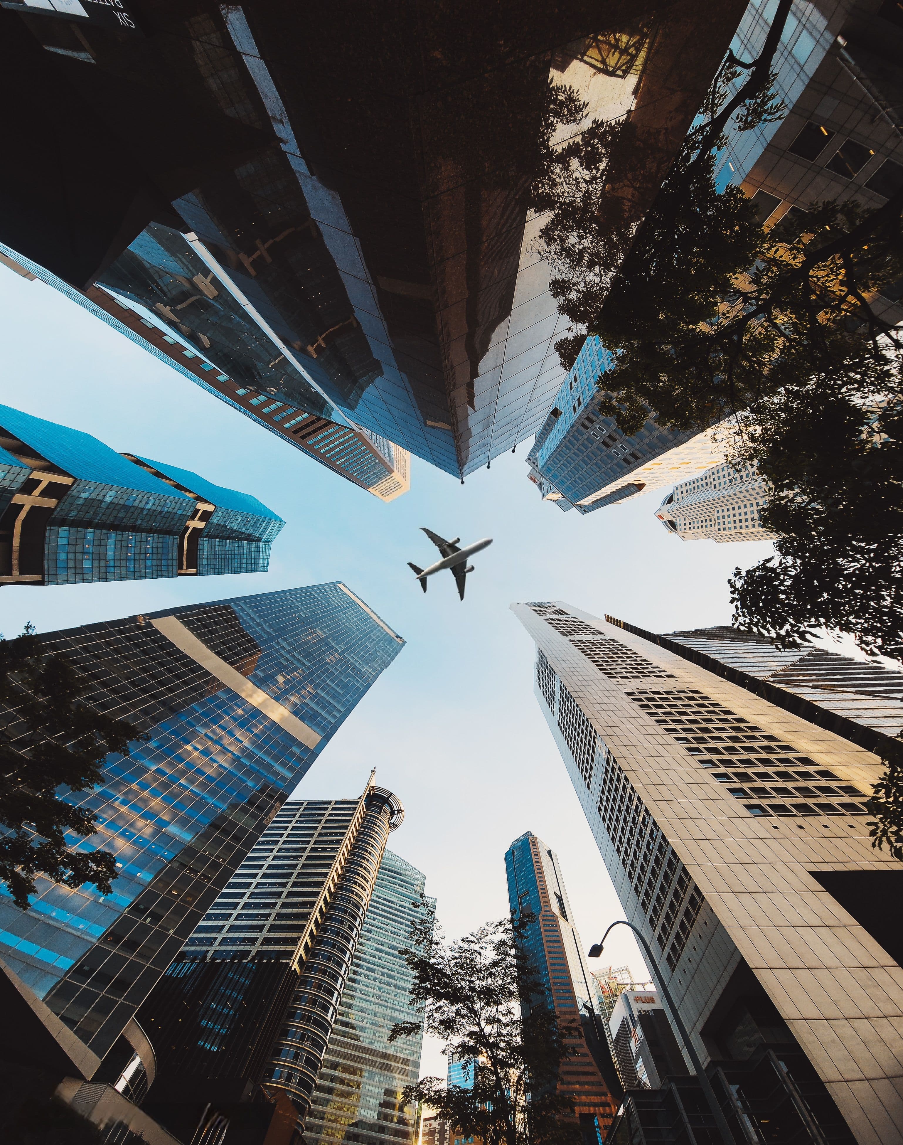 Aircraft flying over city skyscrapers, viewed from below